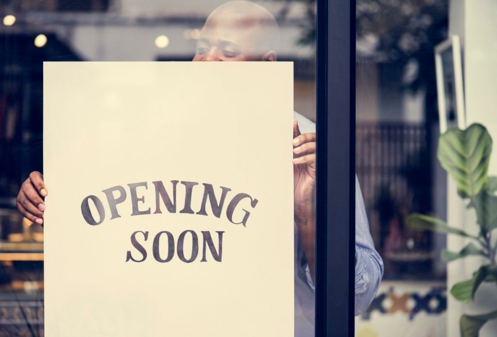 Man putting on store opening soon sign