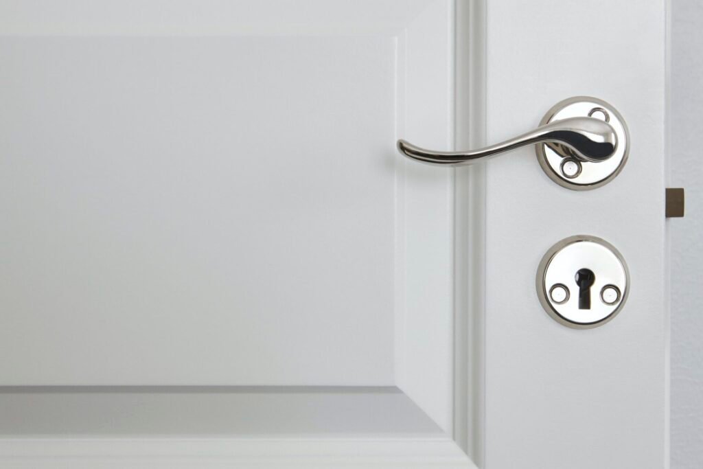 Metallic door knob on a classic white door. Home interior